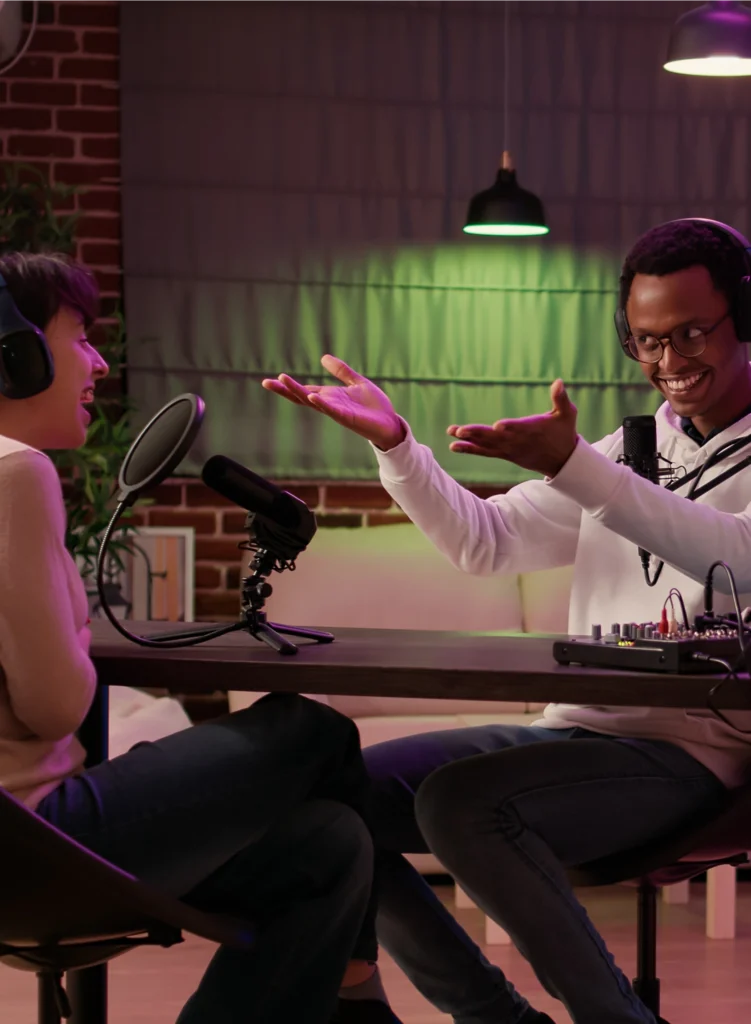 “Podcast hosts recording a professional video podcast with microphones, lights and branded backdrop.”